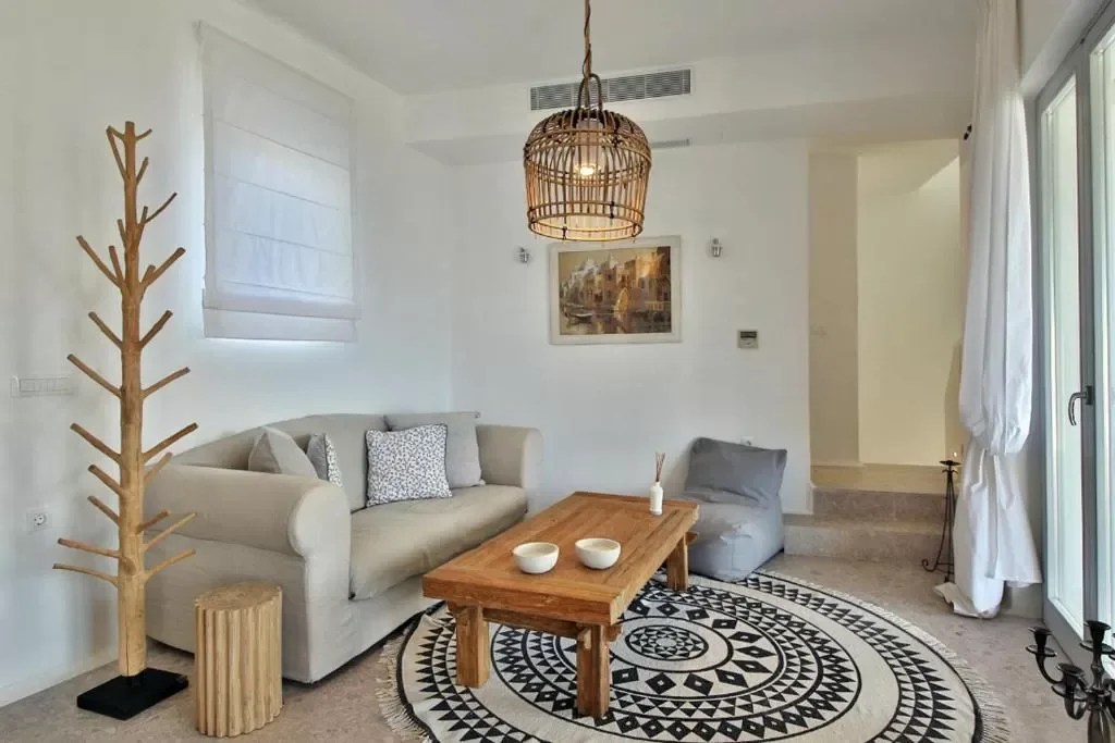 White living room with a timber coffee table and woven pendant light