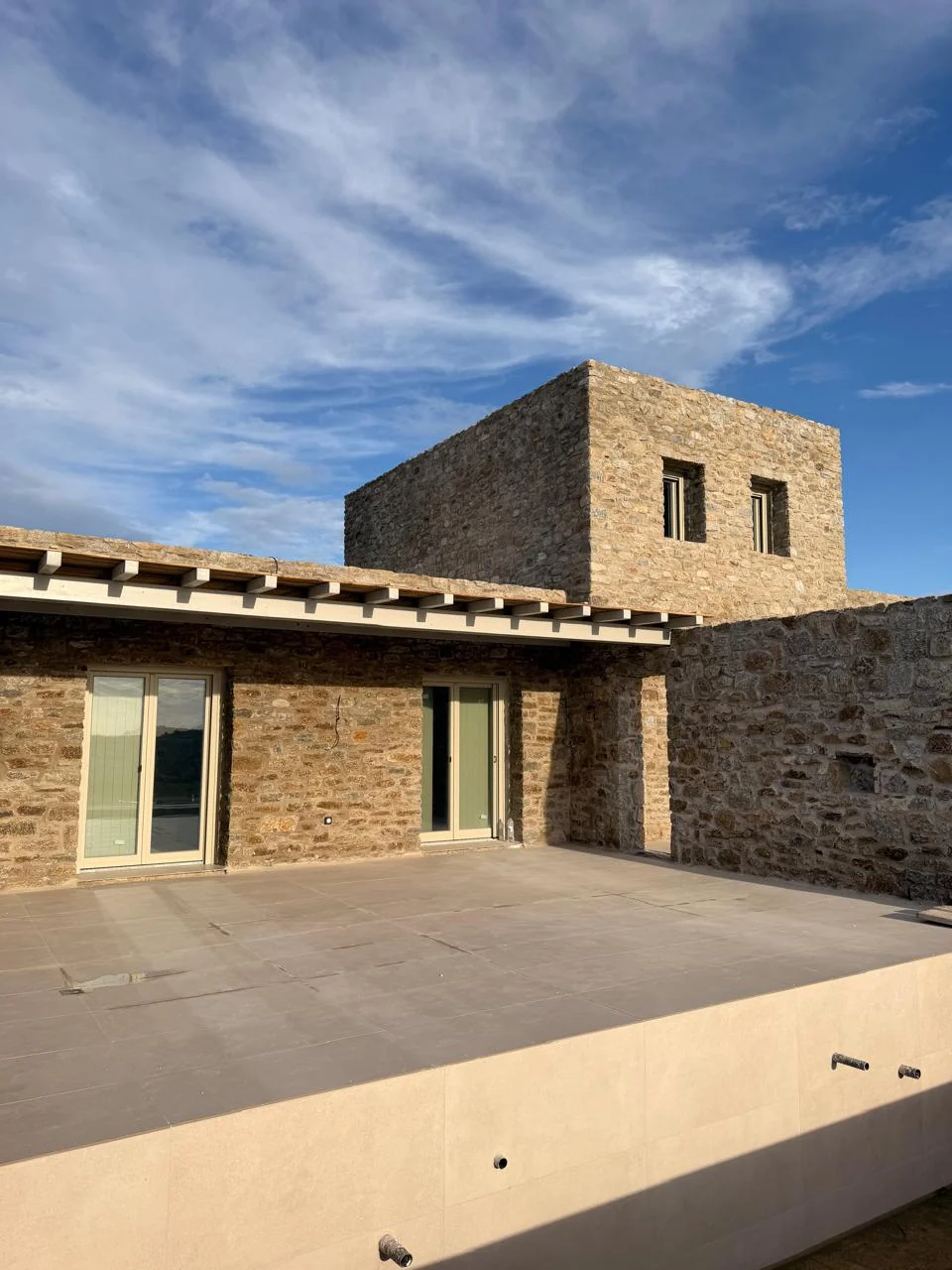 Paragka, Mykonos · Stone residence and sunlit terrace beneath a blue sky.