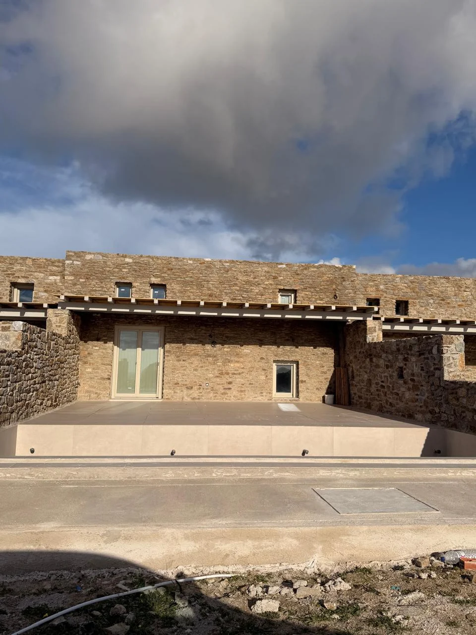 Paragka, Mykonos · Stone facade and broad paved terrace.