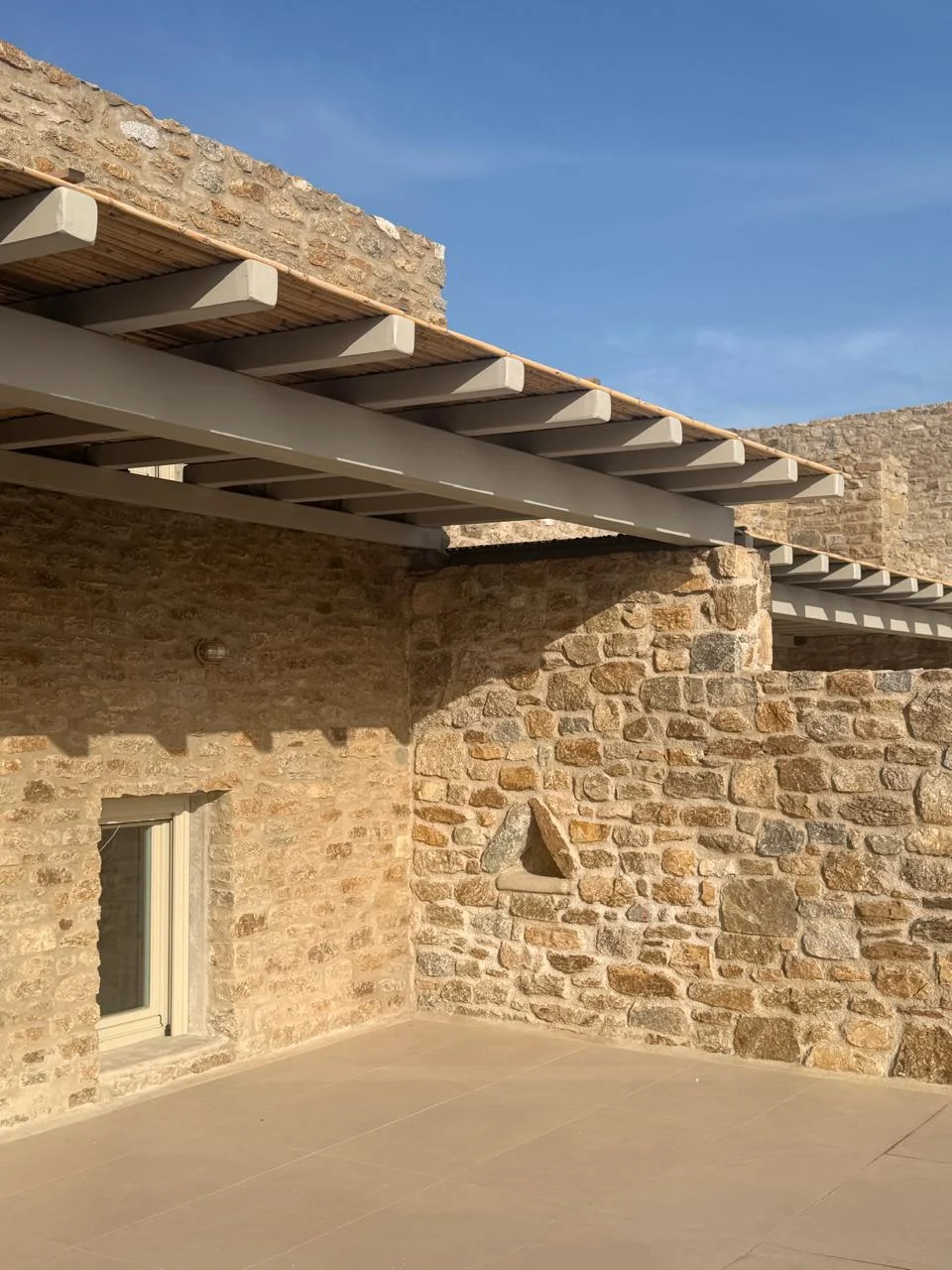 Paragka, Mykonos · Timber pergola and traditional stone exterior.
