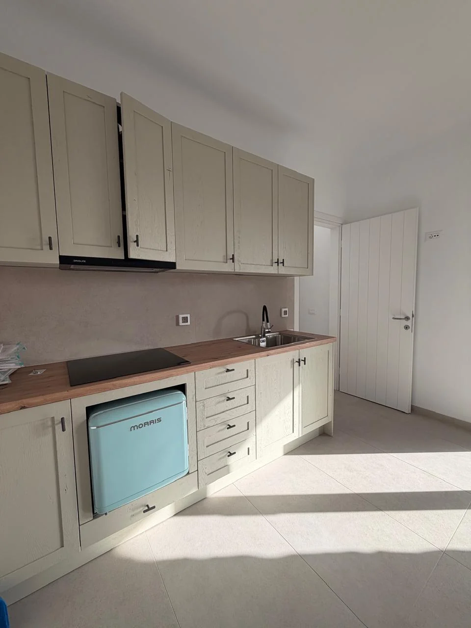 Paragka, Mykonos · Light-filled kitchen with pale cabinetry and timber worktop.