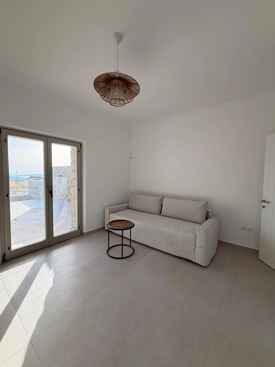 Paragka, Mykonos · Light-filled living space opening to an outdoor terrace.