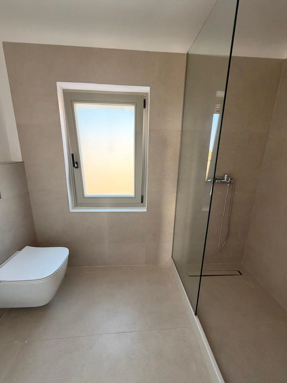 Paragka, Mykonos · Bathroom with glass shower enclosure and tall window.