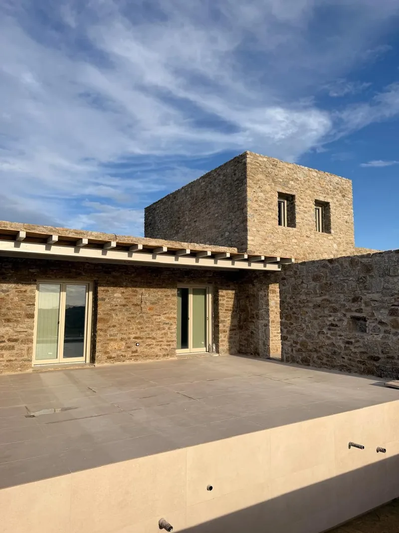 Paragka Residences, Mykonos · Stone residence and sunlit terrace beneath a blue sky.