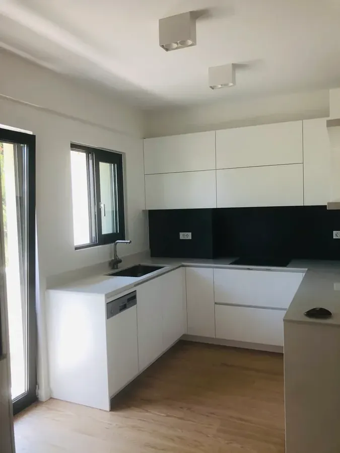 Λευκή κουζίνα με σκούρα επιφάνεια πίσω από τον πάγκο