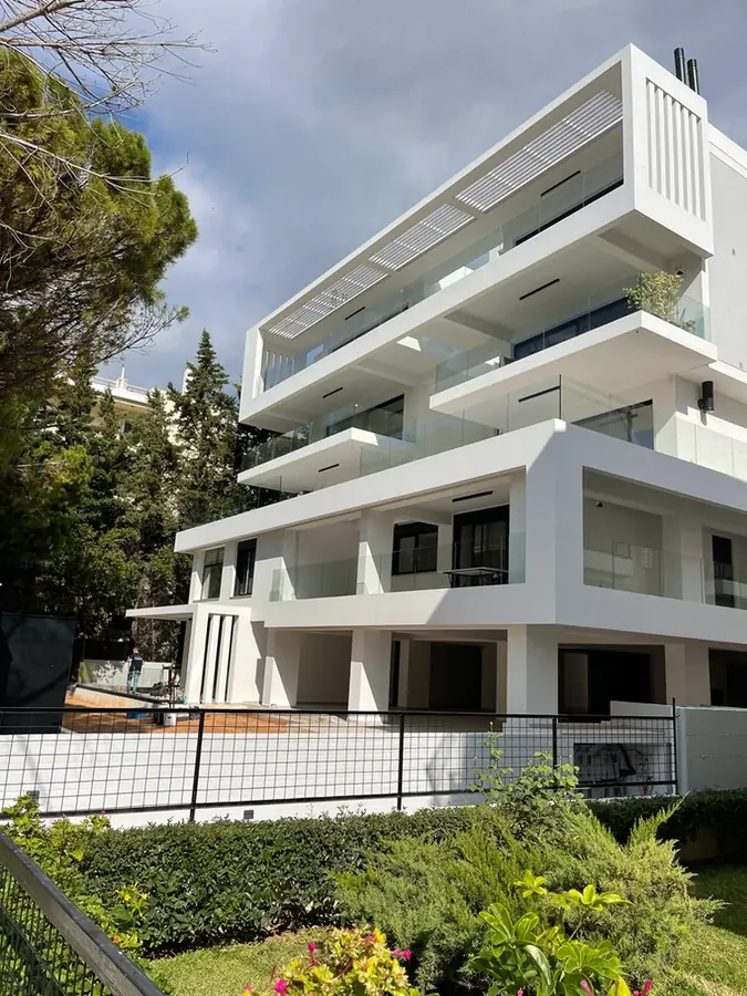 Λευκή κατοικία με βαθιές βεράντες και φυτεμένο όριο