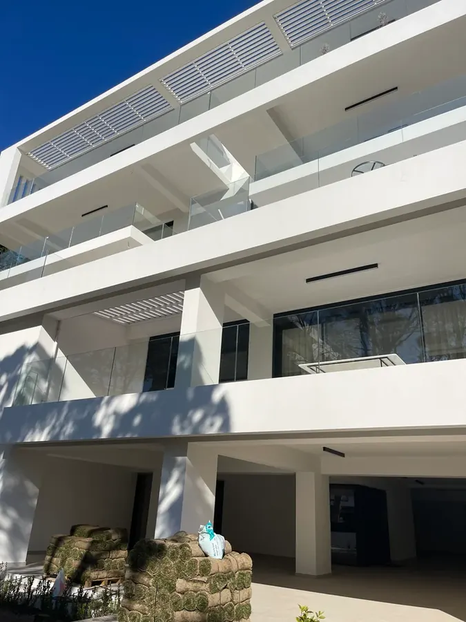 Βαθιά λευκά μπαλκόνια πάνω από είσοδο στο επίπεδο του κήπου