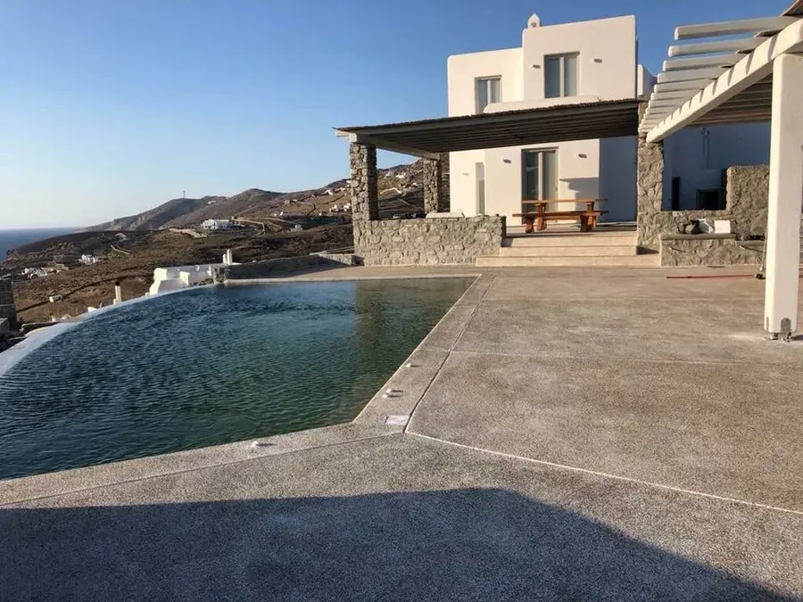 Πισίνα δίπλα σε λευκή βίλα και πέργκολα